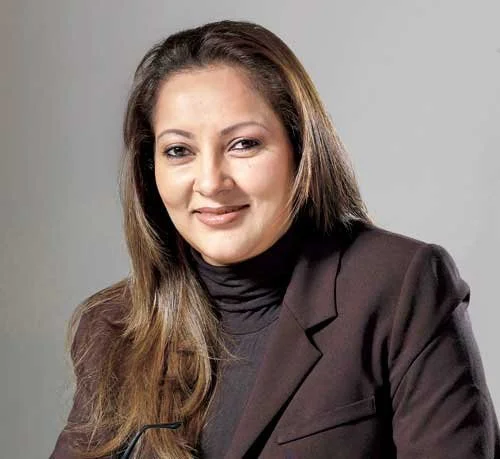 Professional woman with long brown hair wearing a black turtleneck and dark blazer, smiling at the camera.