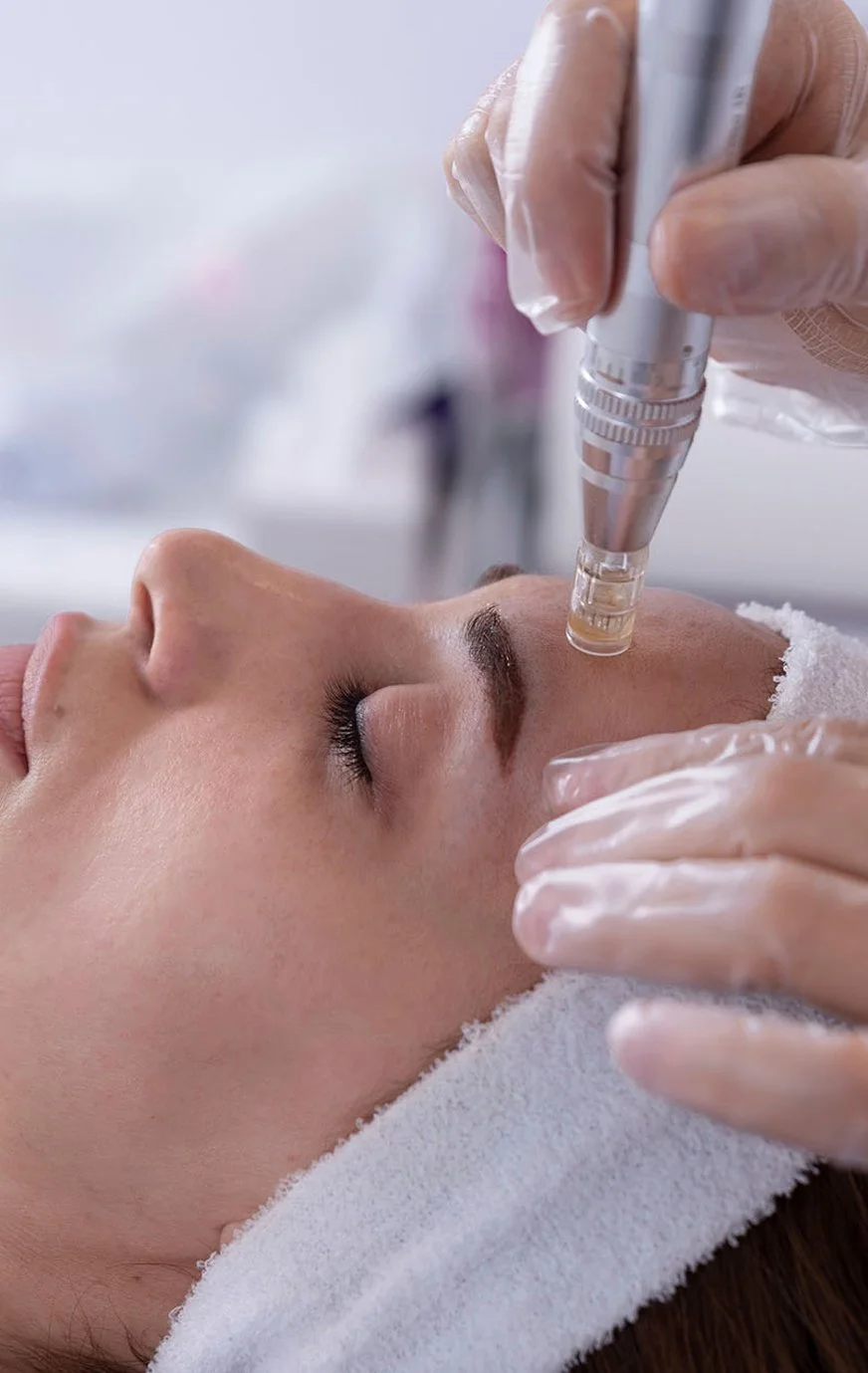 A woman receiving a facial treatment with a cosmetic device on her forehead in a skincare clinic.