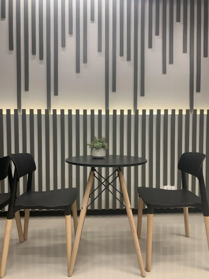 Sales consultation area with minimalist table setup, accent wall design, and modern black chairs.