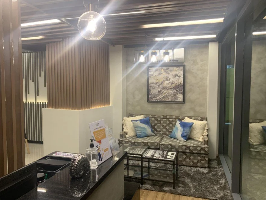 Office lounge with wood-slat ceiling, black chairs, and decorative console table with mirror.