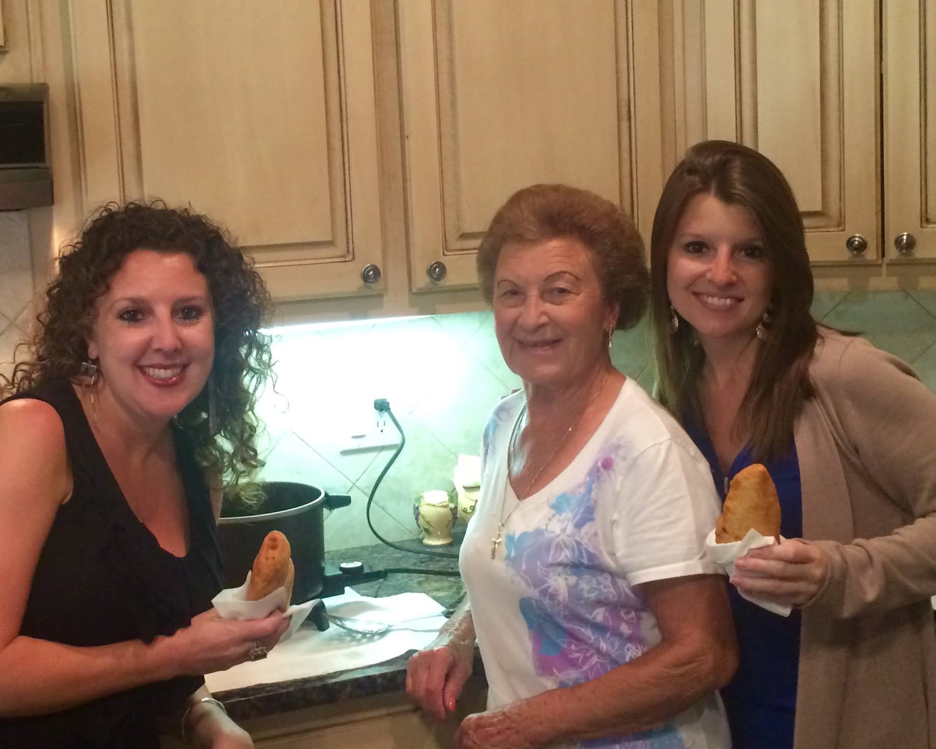 Three young women with their grandmother in the kitchen making panzerottis.