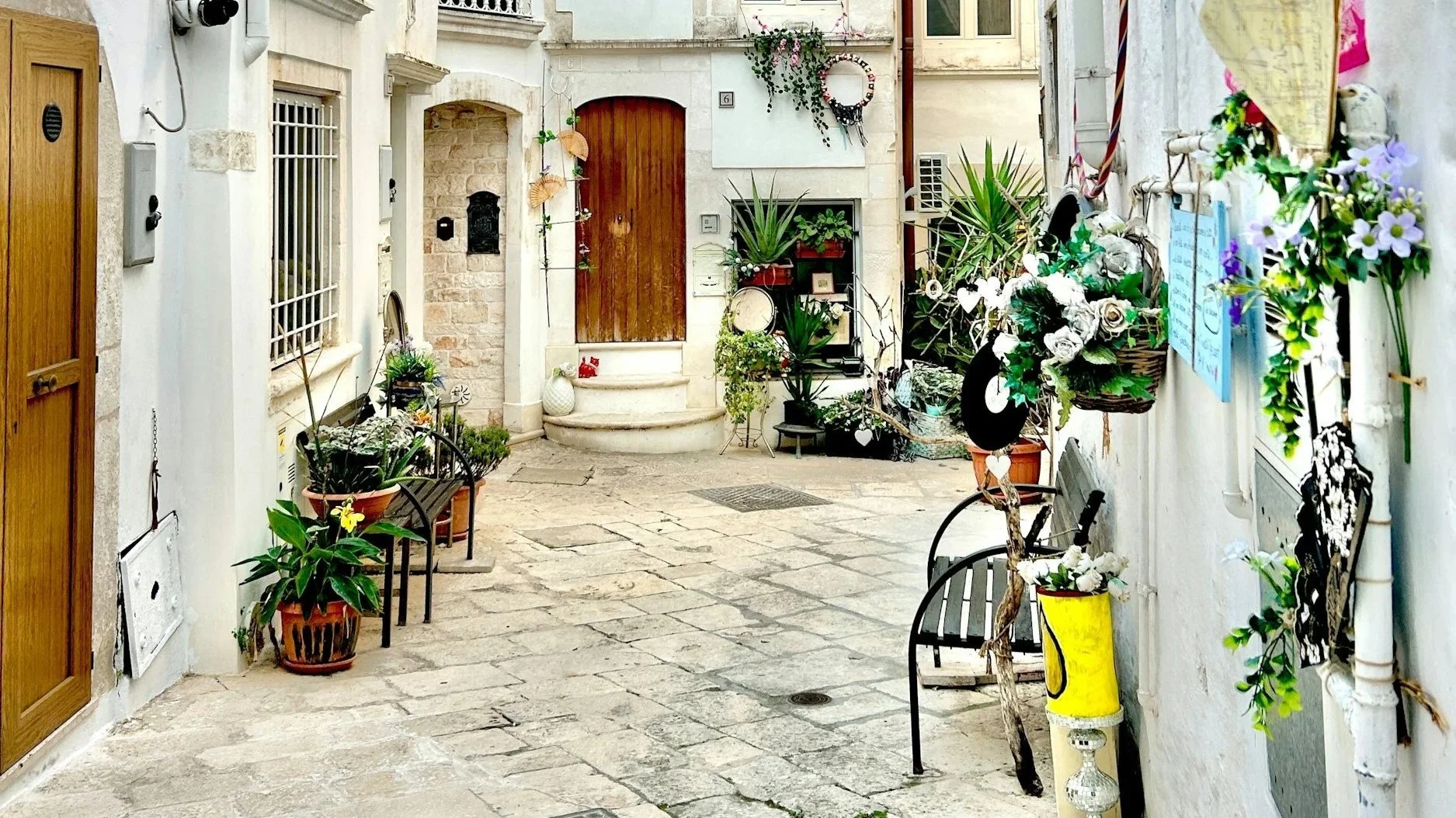 Cobblestone alleyway in Italy surrounded by greenery.