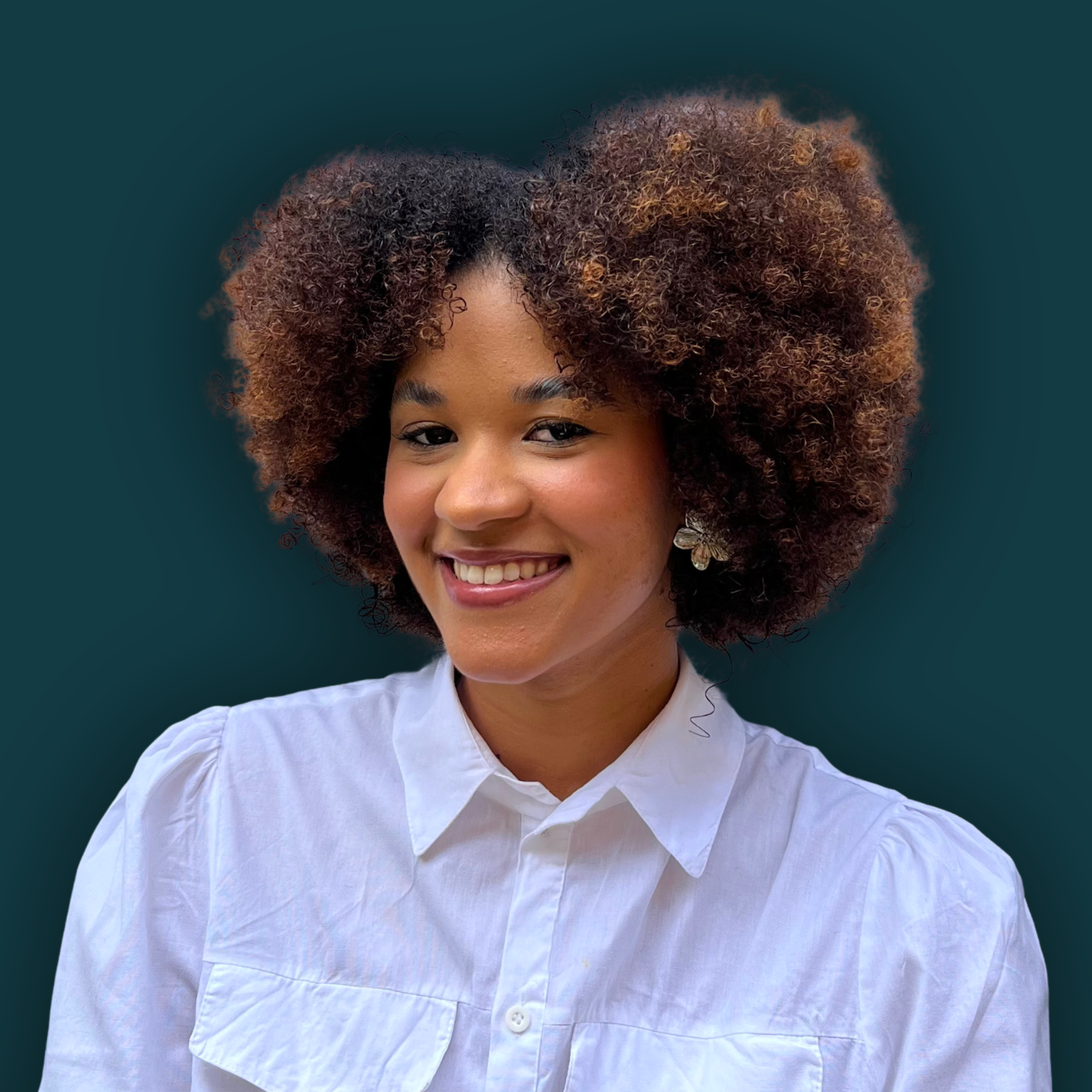 Close-up of a woman with curly, reddish-brown hair, smiling, wearing a white shirt, against a solid dark teal background.