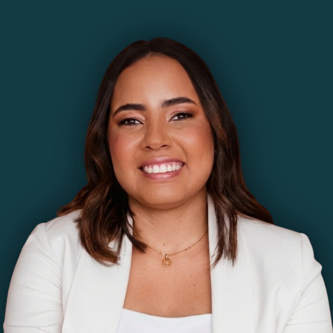 Professional woman with shoulder-length dark brown hair, wearing a white blazer and gold necklace, smiling against a dark teal background.