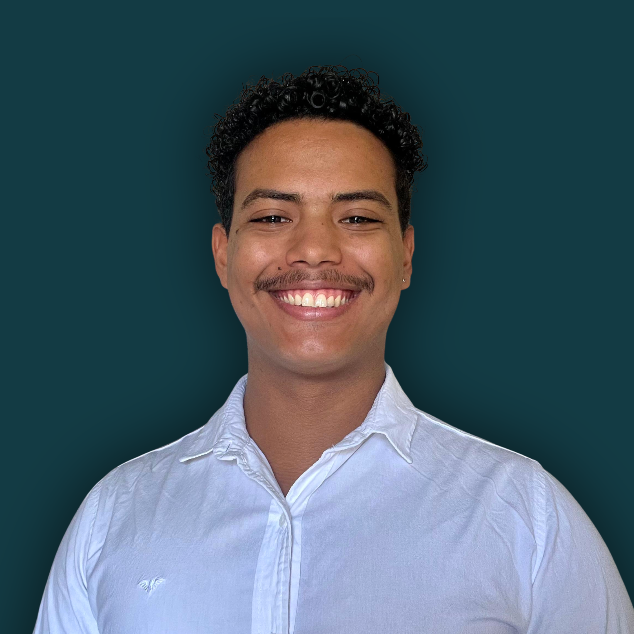 Portrait of a smiling young man with curly hair, mustache, wearing a white button-up shirt, against a dark teal background.