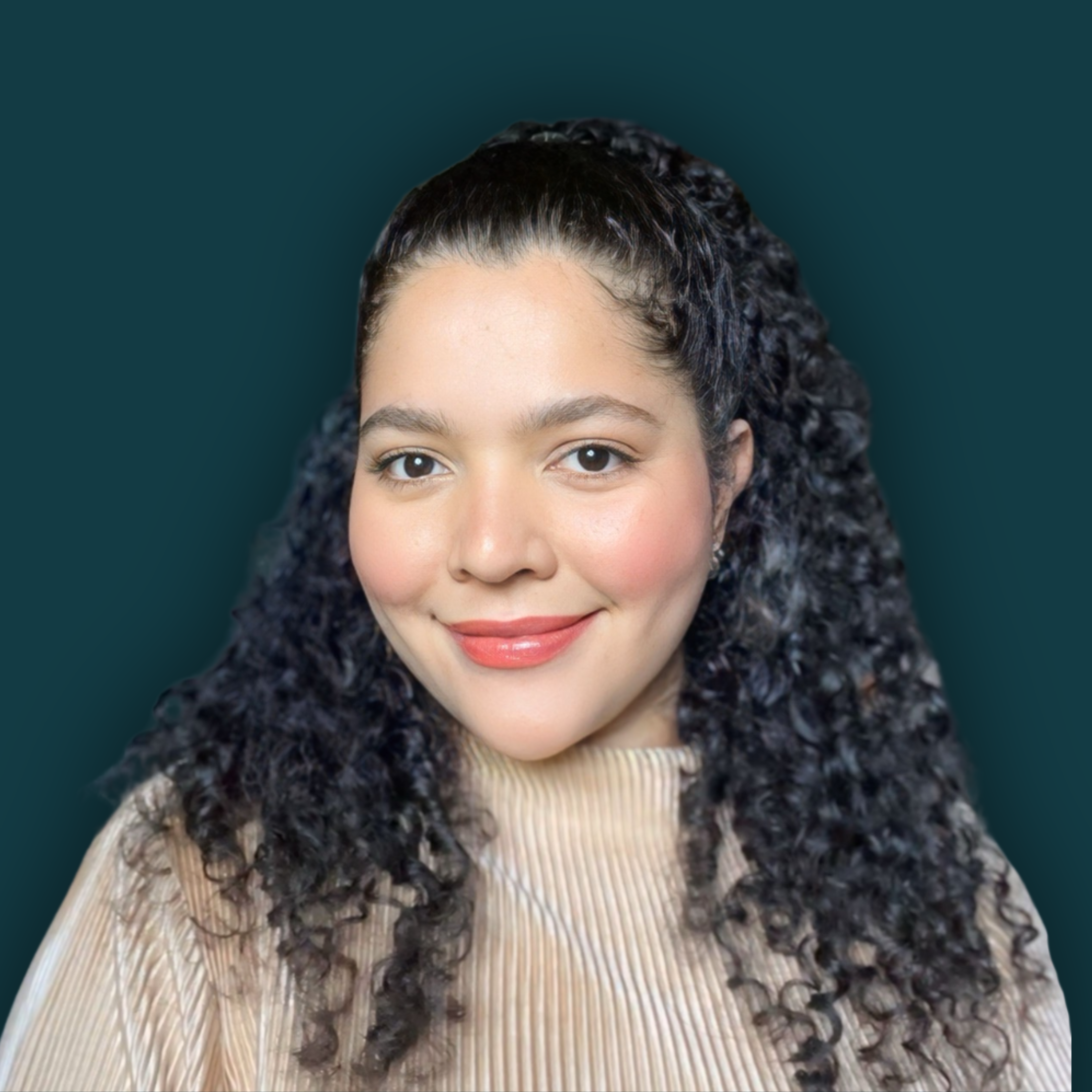 A woman with curly hair, smiling, wearing a beige ribbed top.