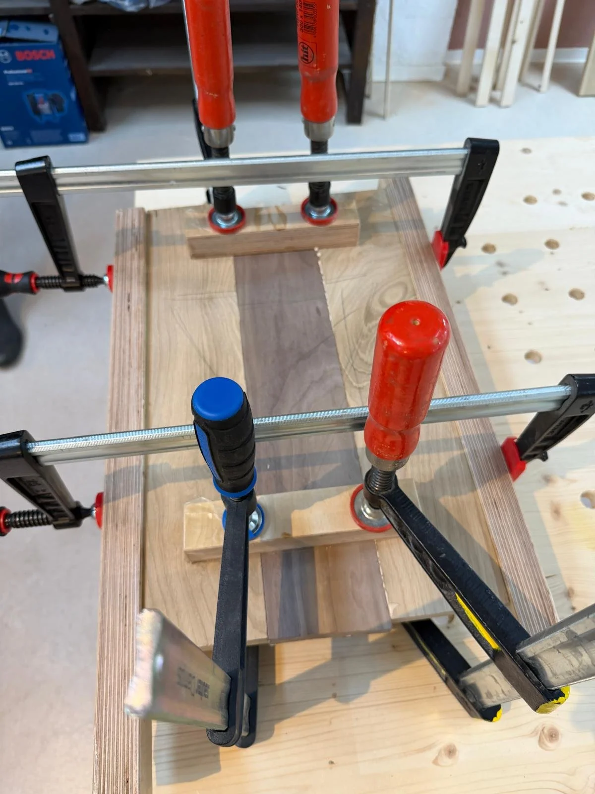 Werkzeugklemmen, die auf einer Holzplatte in einer Werkstatt befestigt sind.