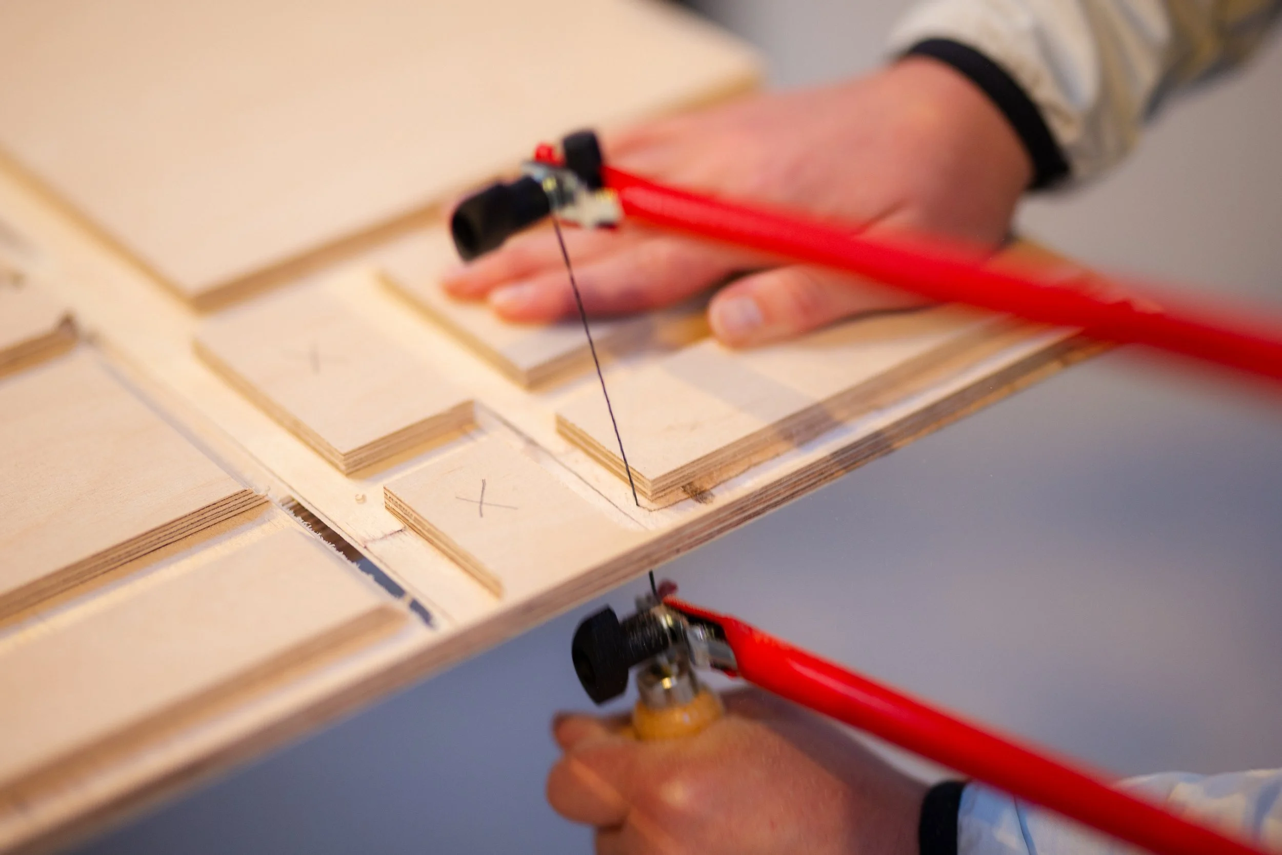 Handwerkliche Tätigkeit beim Zusammenbauen eines Holzmodells mit einer Staubmaschine.