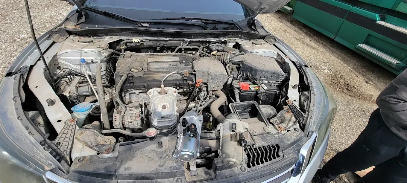 View of a car engine with the hood open, showing various engine components and parts.