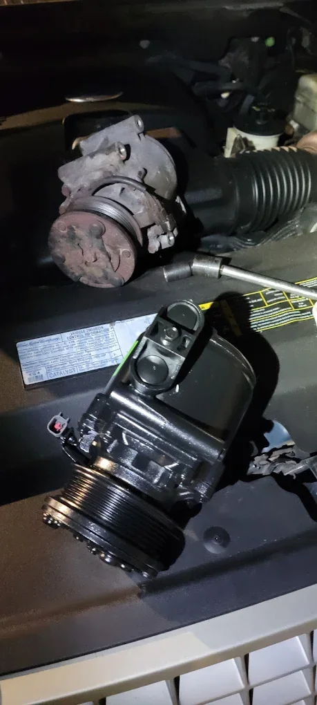 A car air conditioning compressor removed and placed on a table.