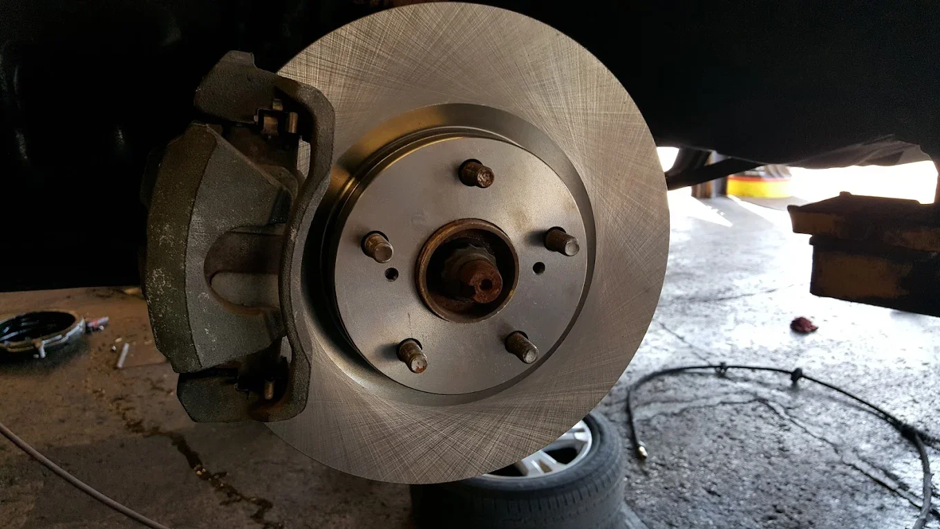 Close-up of a car's front brake assembly with the wheel removed, showing the brake disc and caliper.