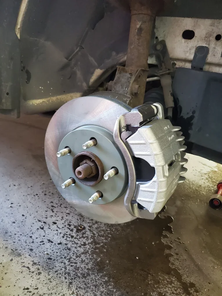 Close-up of a car's front brake disc and caliper assembly after installation, with the wheel removed.