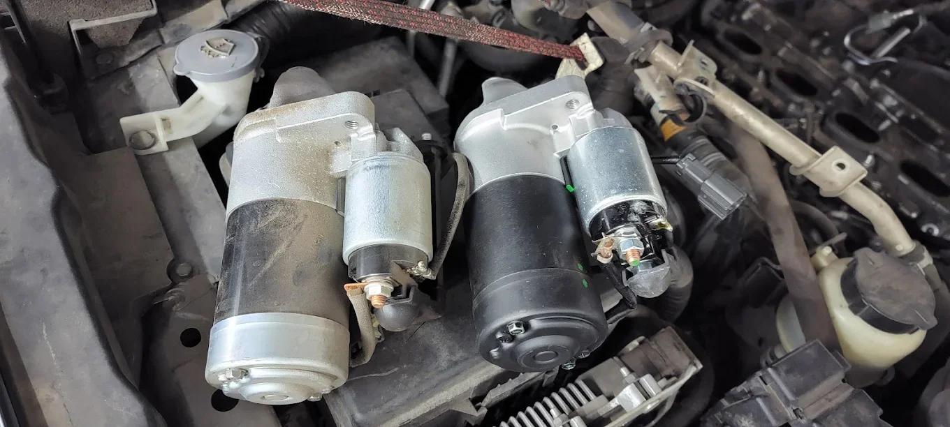 A pair of car starter motors installed in a vehicle's engine bay.