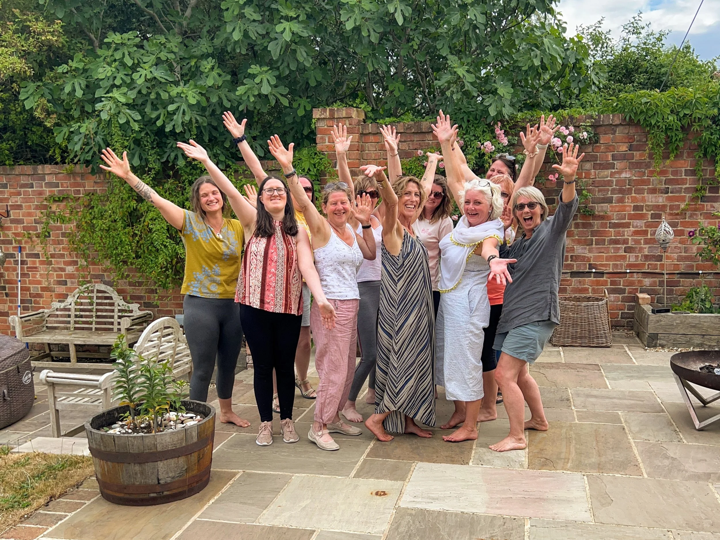 A group of people standing outdoors on a patio, smiling and celebrating with their hands raised.