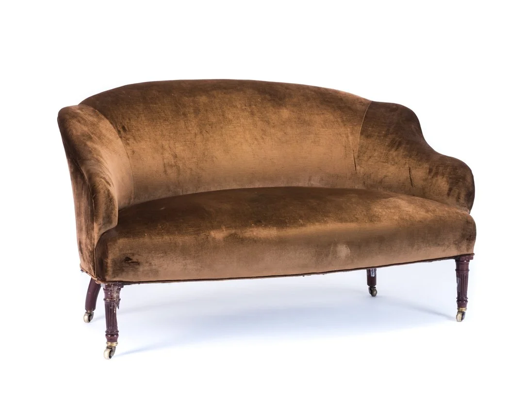 Vintage brown velvet sofa with wooden legs and casters.