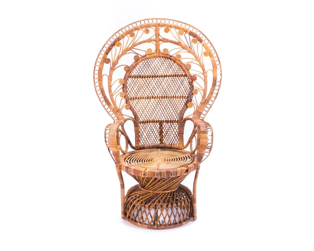 A wicker peacock chair with a large, ornate backrest featuring intricate woven patterns, circular and spiral details, and a high, arched shape.