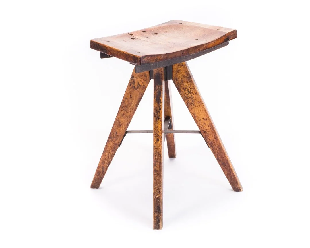 Rustic wooden stool with three legs against a white background.