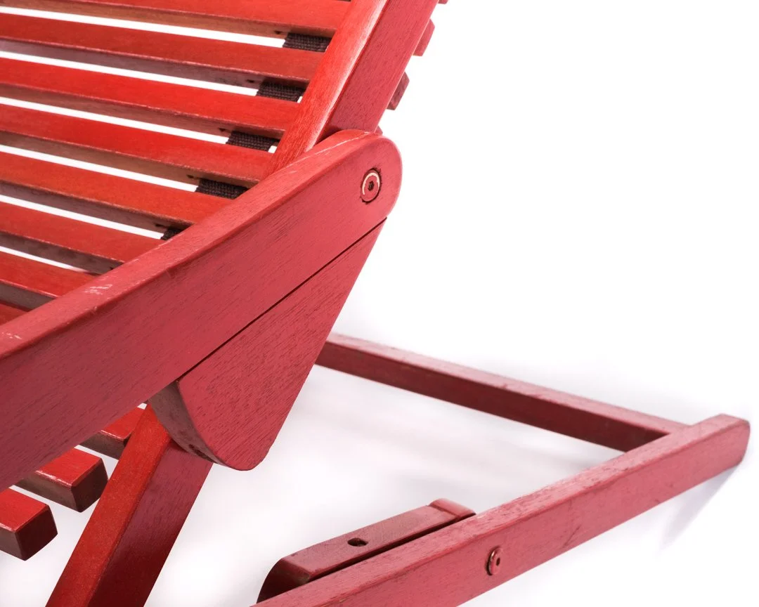 Close-up of a red wooden outdoor bench with slatted design.