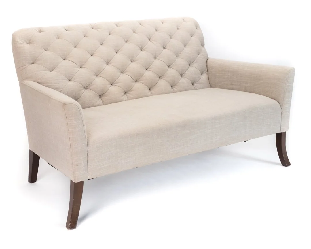 Beige upholstered sofa with tufted backrest and dark wooden legs.