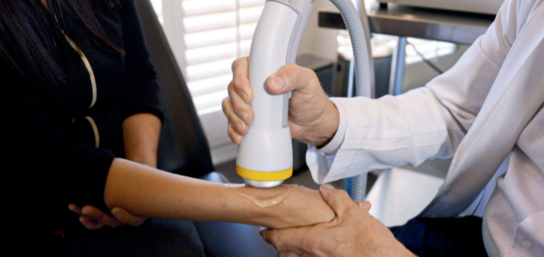 Doctor using a softwave machine to treat a patient using non-invasive therapy. Non-surgical