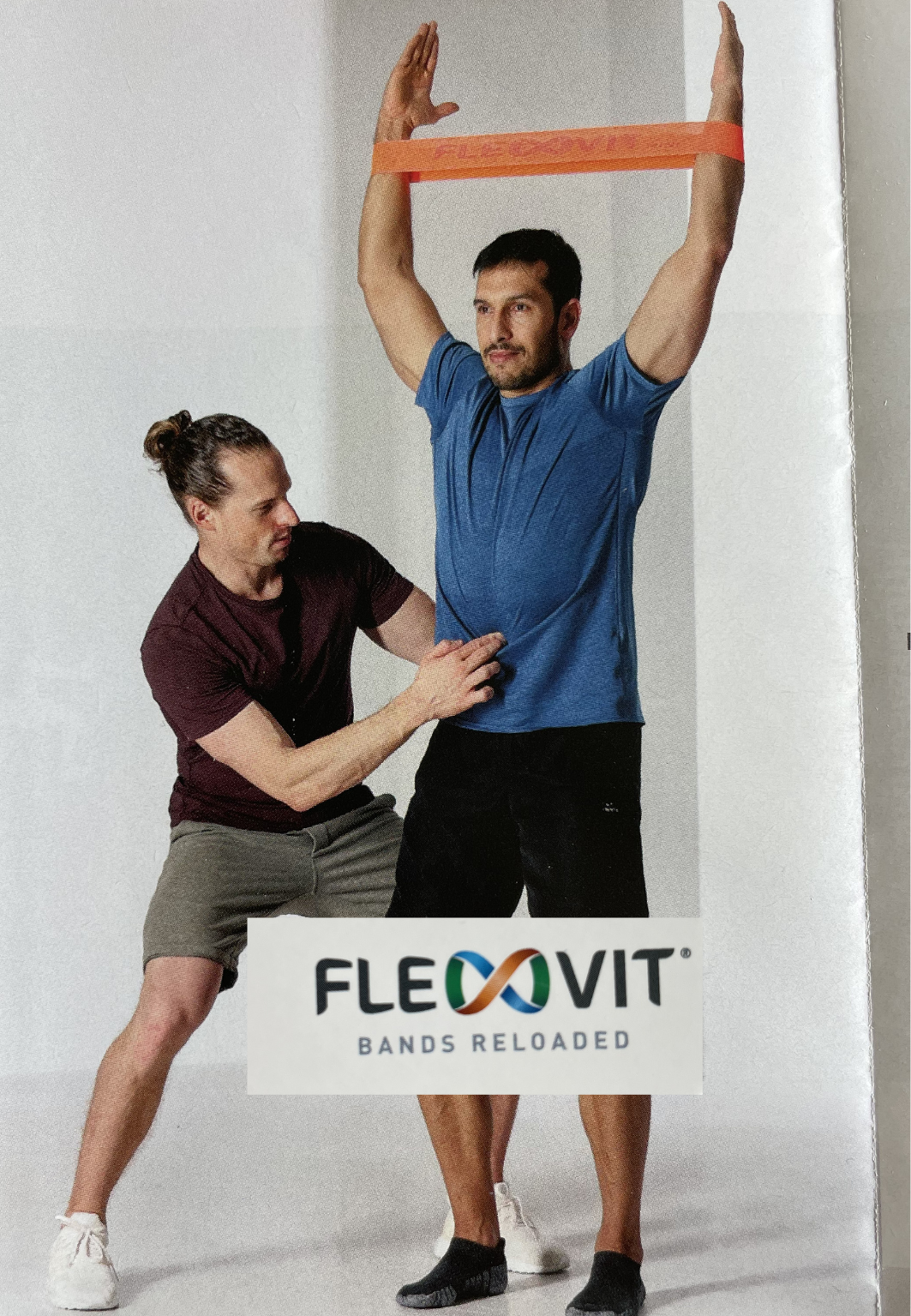 Ein Trainer korrigiert einen Mann bei seinen Fitnessübungen mit einem Flexvit Band