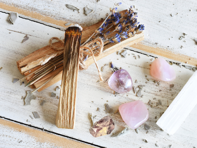 Lavendel, Palo Santo und Edelsteine liegen auf einem Holztisch