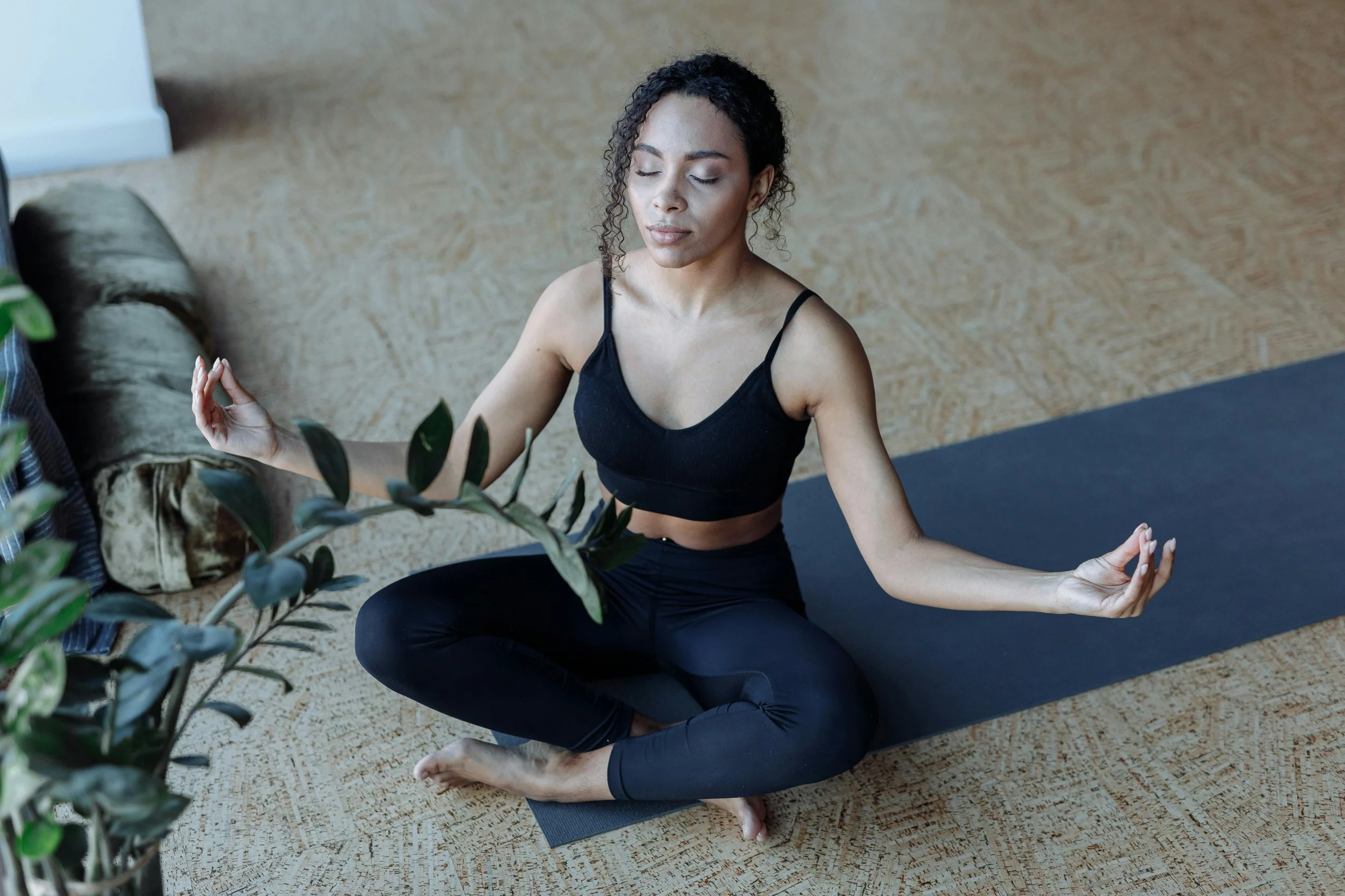 Frau sitzt auf Yogamatte und führt Pranayama/Breathwork aus