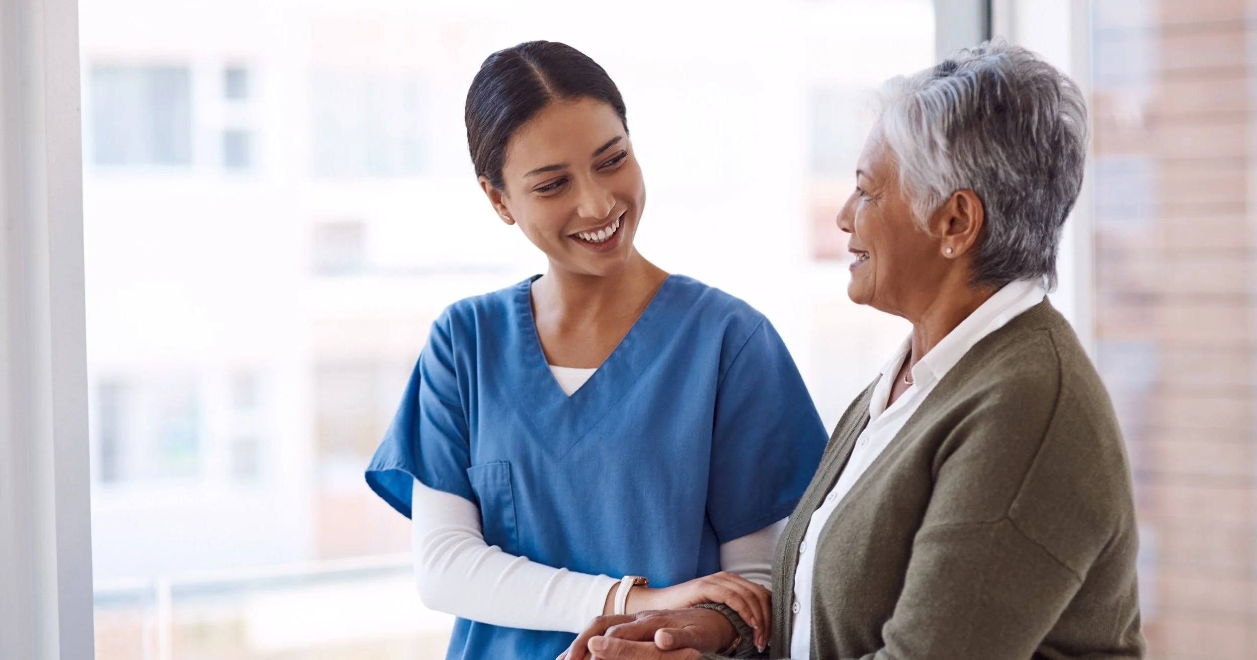 support-caregiver-with-senior-woman-holding-hands-care-indoors-retirement-consulting-professional-female-nurse-with-elderly-person-smiling-together-healthcare-nursing-home.jpg