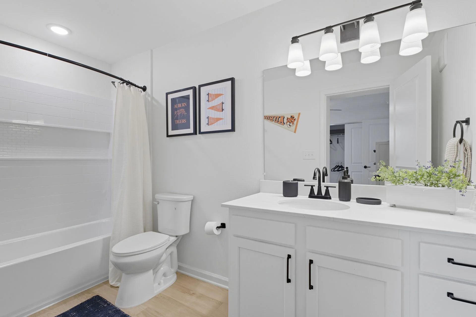 Modern white bathroom with black fixtures, decor, and a large mirror