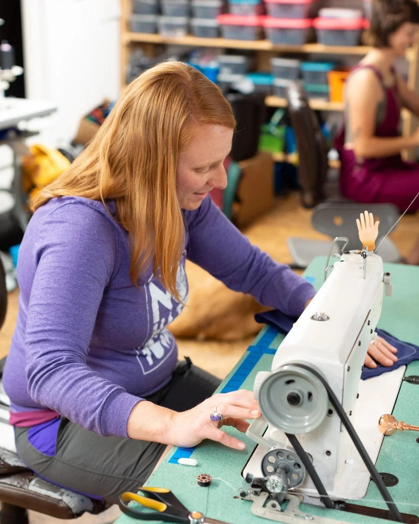 Woman sits at sewing machine