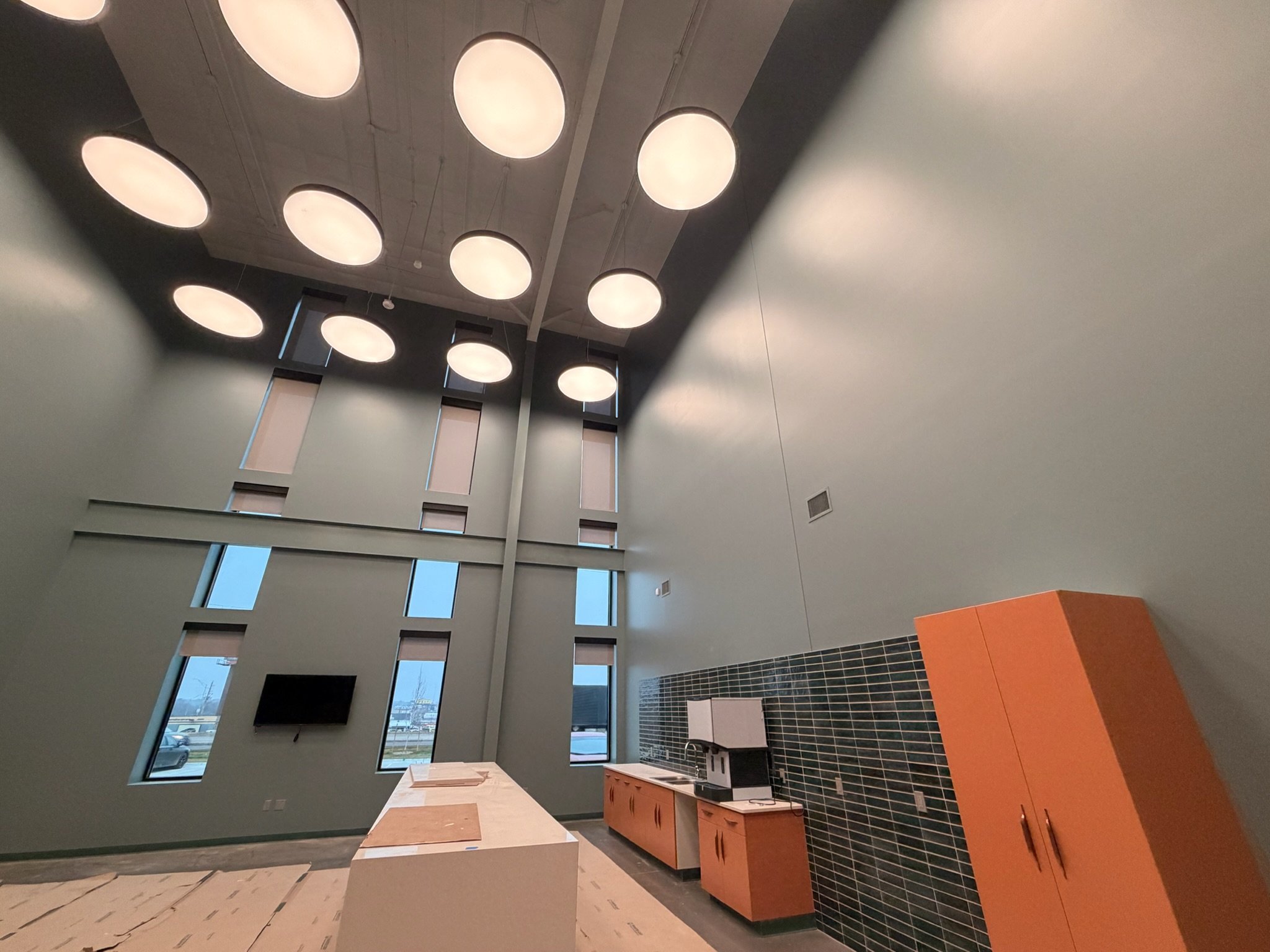 Commercial break room with painted orange cabinetry and black tile backsplash