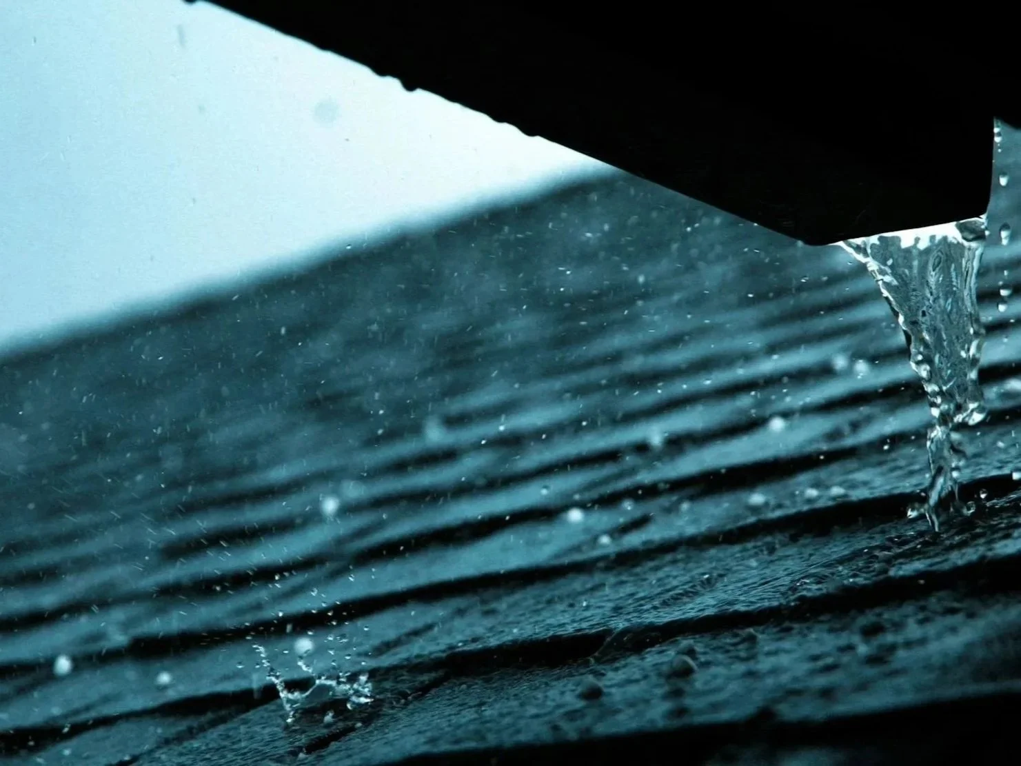 A close-up of water dripping from an object onto a textured surface.