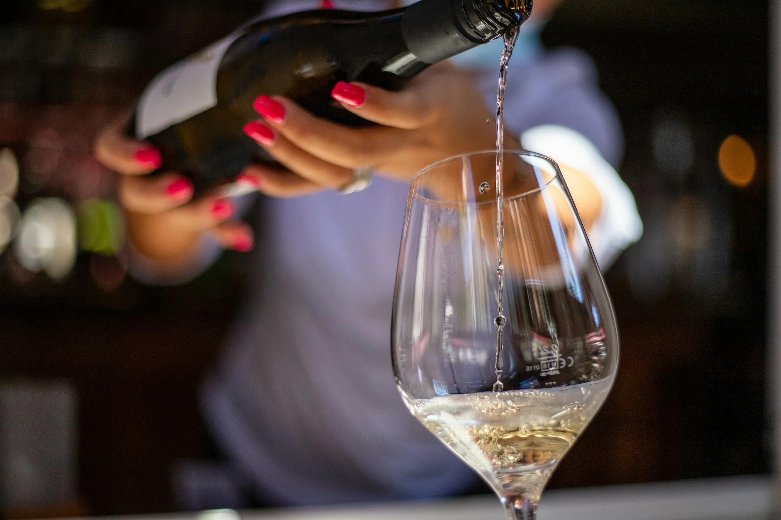 Sommelier pouring a tasting pour of white wine at Wine Wednesdays at Lucky Hare