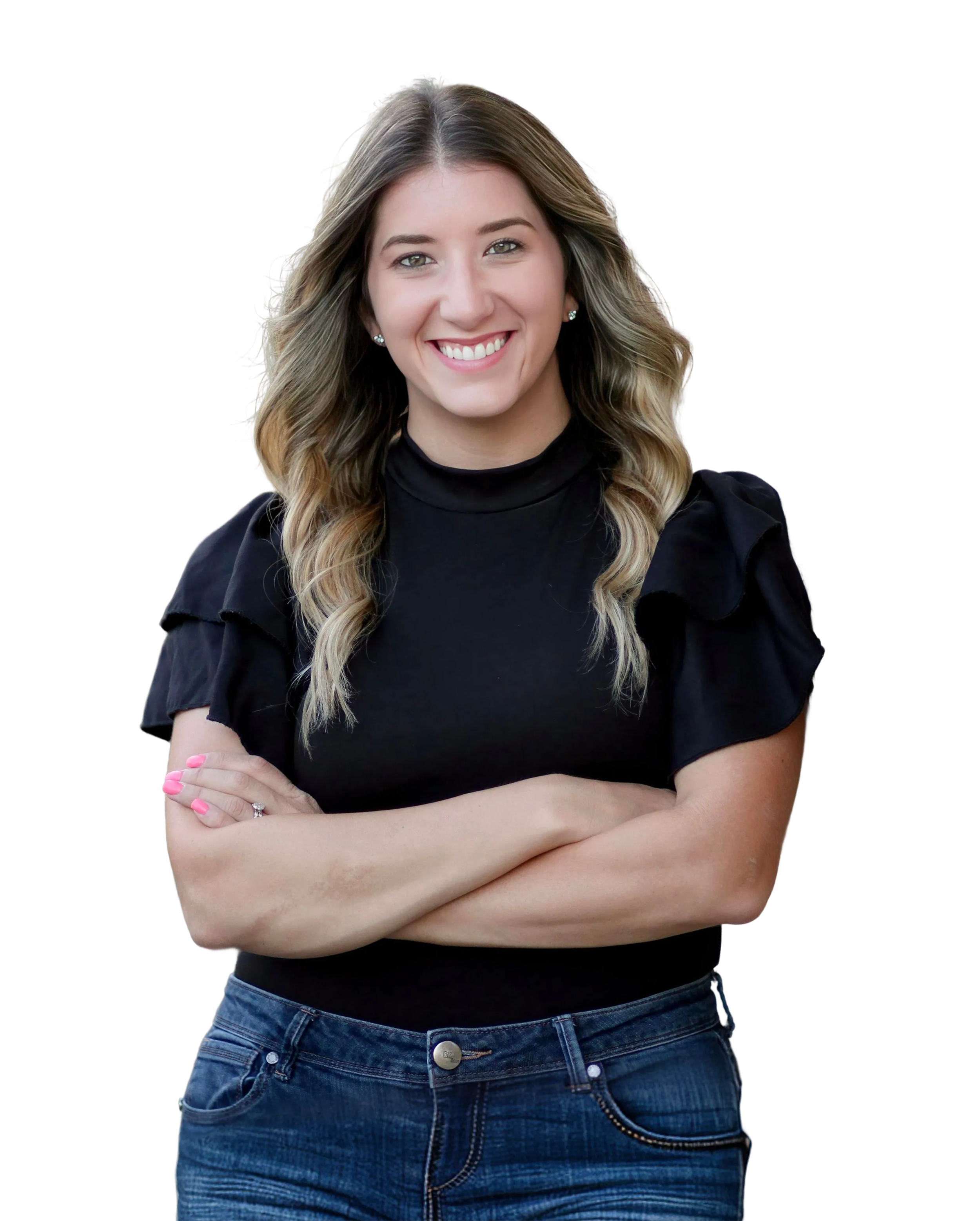 Mental health therapist, Jennifer Torres,  wearing a black top with ruffled sleeves and blue jeans, standing with her arms crossed and smiling.