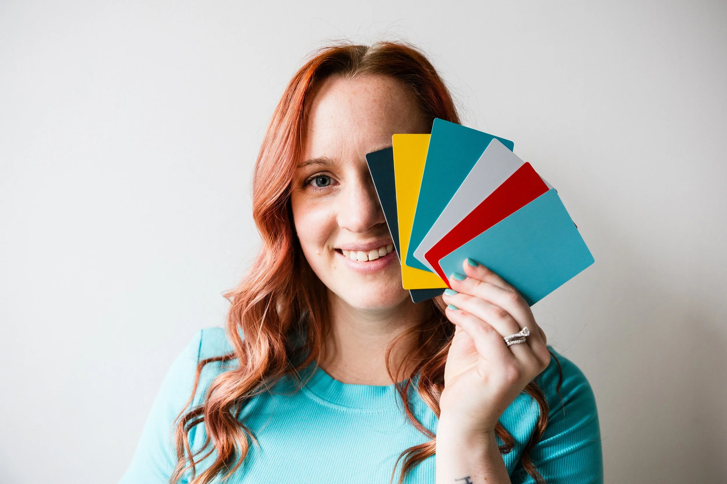 Kristen holding up color palette cards in dark blue, teal, white, yellow, and red