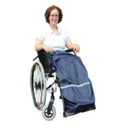 Woman in a wheelchair pulling a shopping cart with a bag.