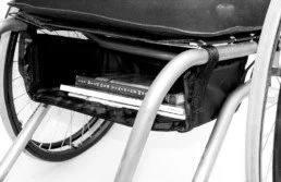 Close-up of a wheelchair's storage compartment with a remote control placed inside.