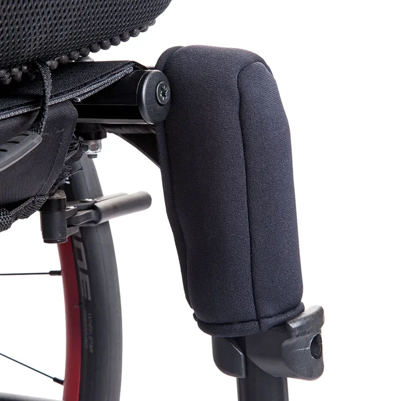 Close-up of a wheelchair’s front armrest and wheel, showing a padded armrest and part of the black frame.