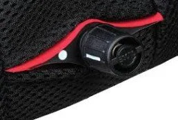 Close-up of a black mesh bag with a built-in red zipper containing a small black flashlight.