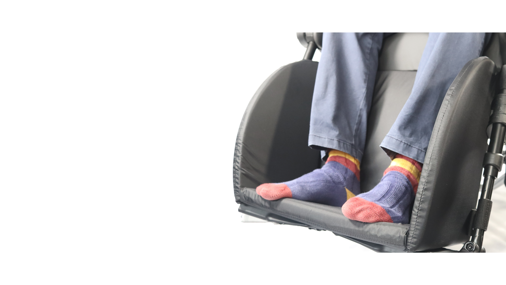 Close-up of a person sitting in a wheelchair with their feet resting on the footrest.