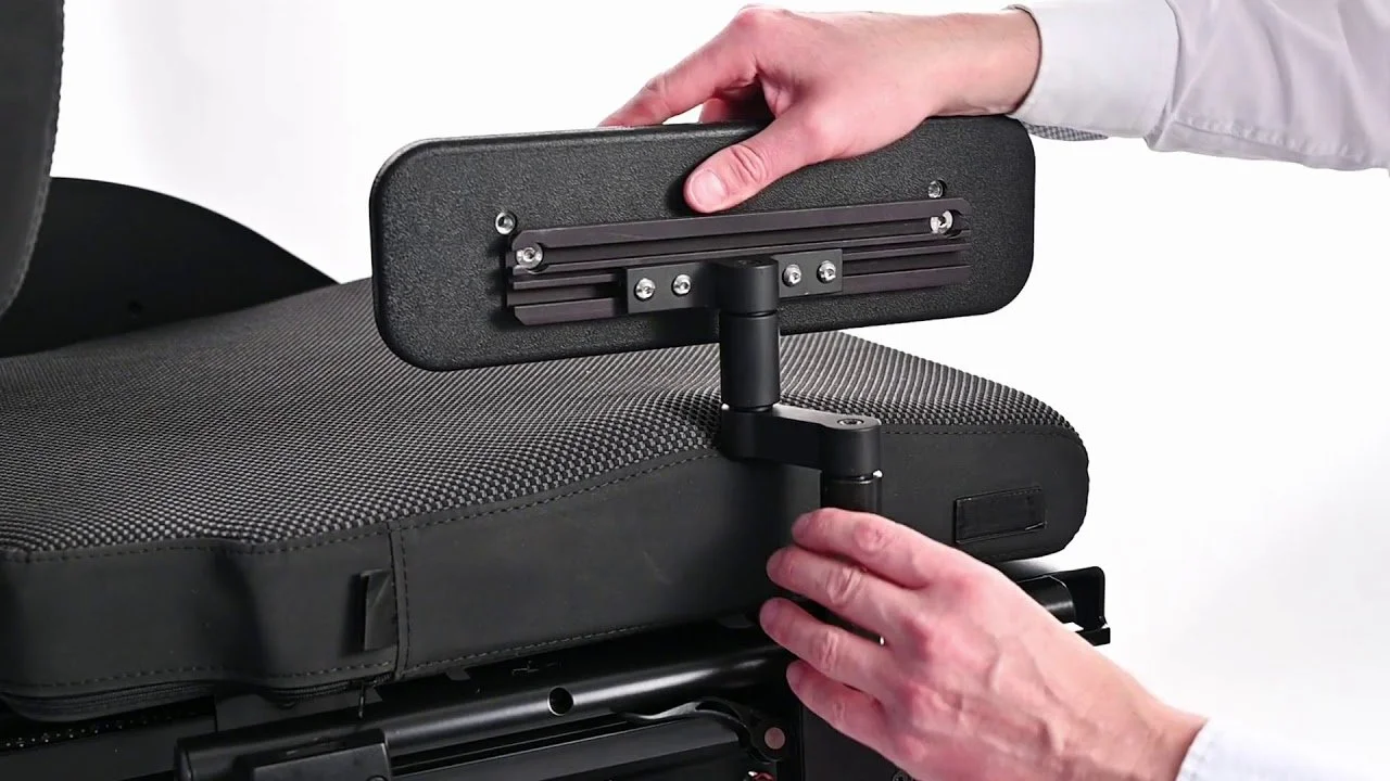 A person adjusting a headrest on a wheelchair with a mechanical support system.