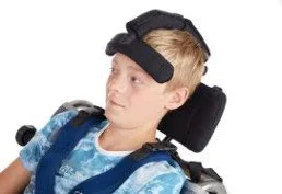 Young boy with a head support device, sitting in a wheelchair.