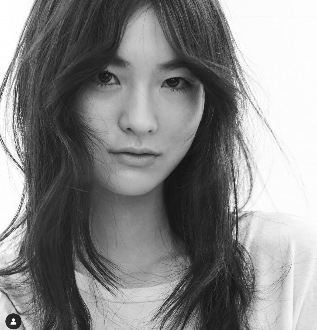 Black and white portrait of a woman with long, wavy hair and intense eyes.