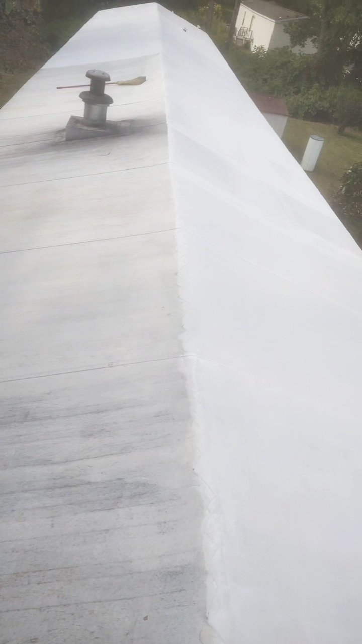 A roof with a pipe vent and a seam, showing parts of the roof before and after being painted or coated.