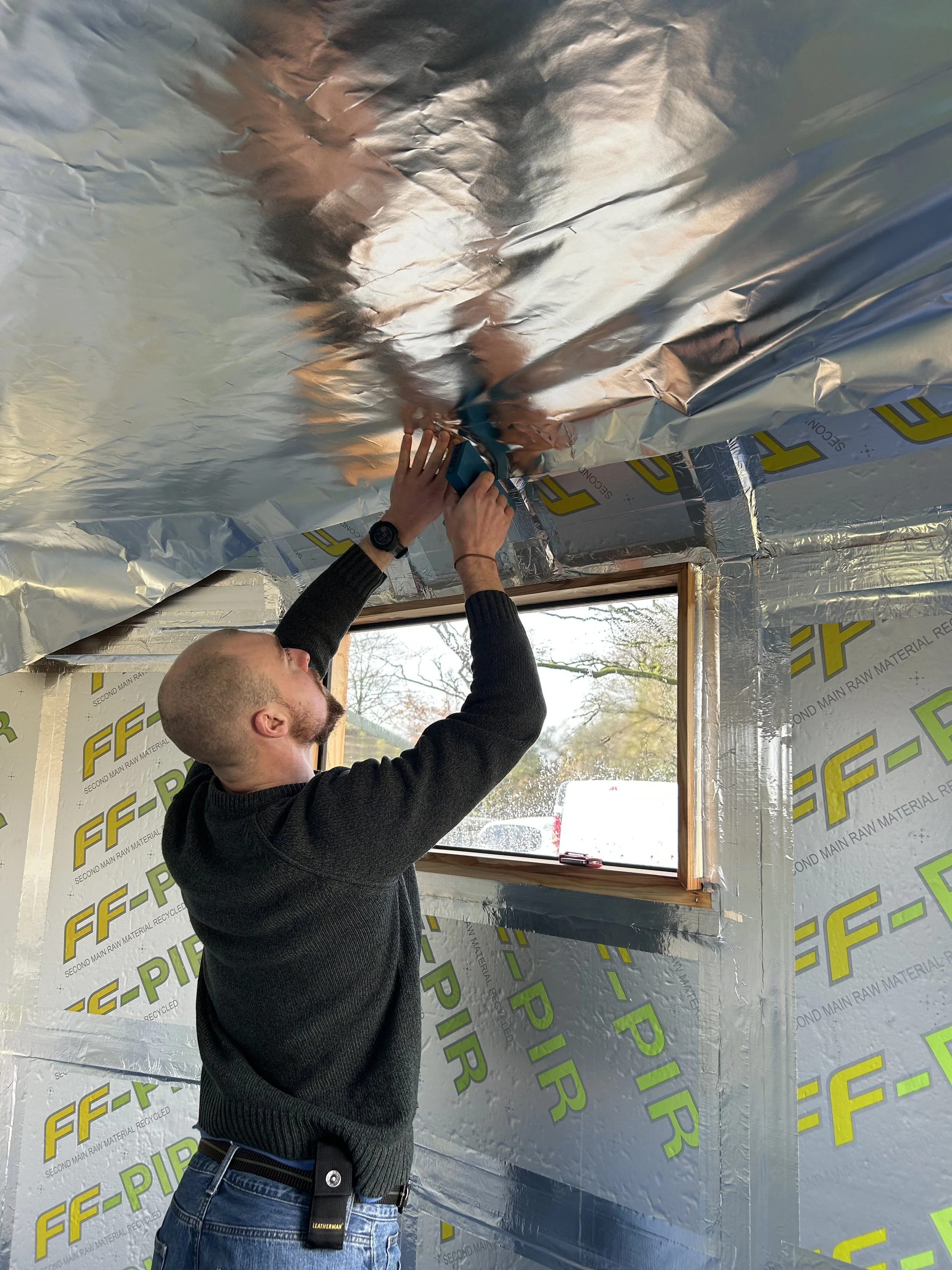 Cameron installing reflective sauna insulation on the ceiling of the Drift Sauna. the sauna is now based at Livit Adventures, near Bideford, Appledore, Westward Ho!