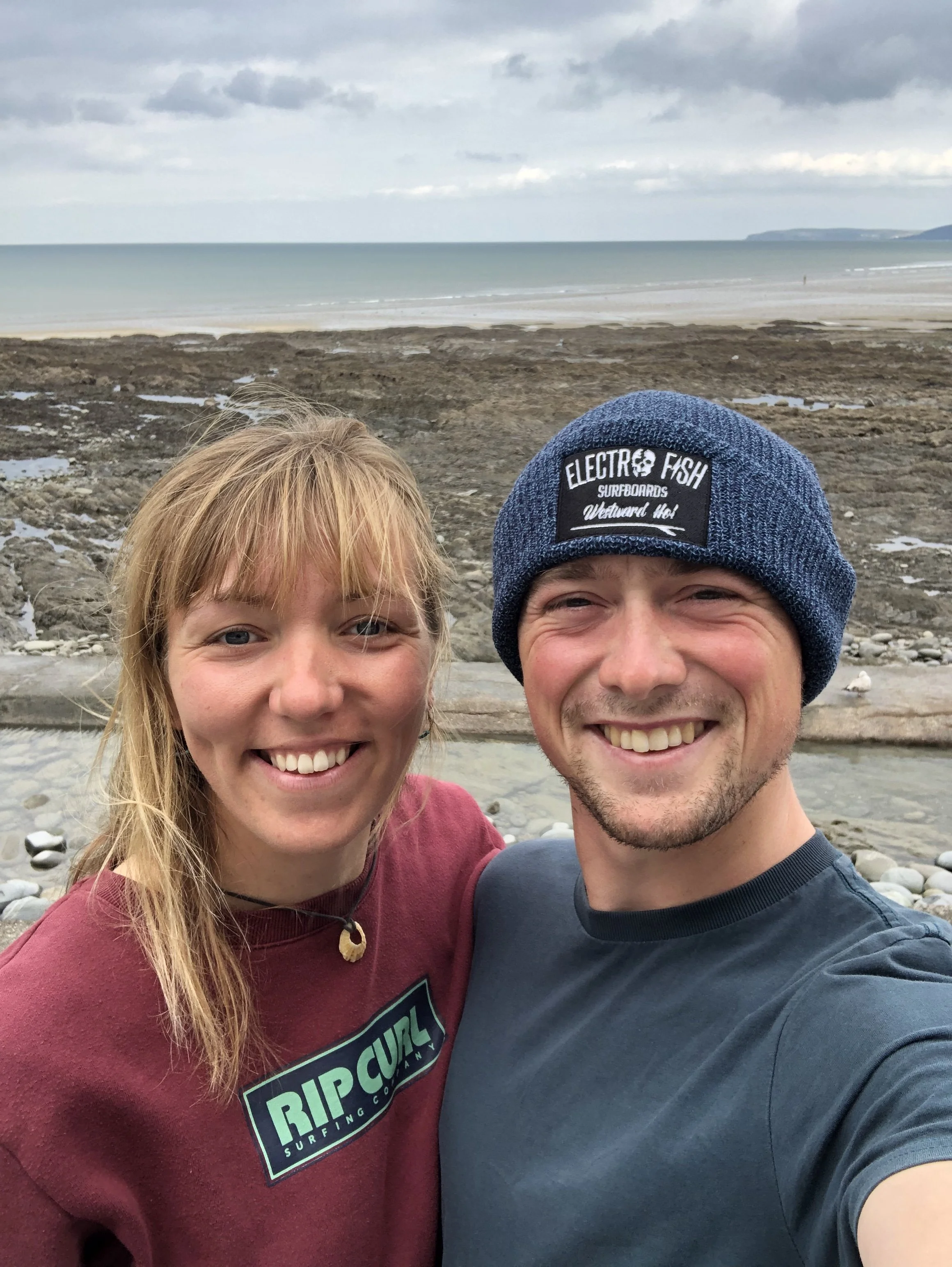 The smiling couple  who operate the Drift Sauna, at Livit Adventure and glamping in Bodeford,  taking a selfie by the Westward Ho! Seapool.