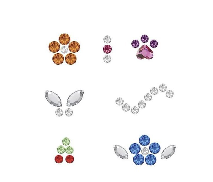 Collection of rhinestones arranged as shapes and symbols, including a flower, a paw print, a butterfly, a smiley face, a cherry, and a flower with leaves.
