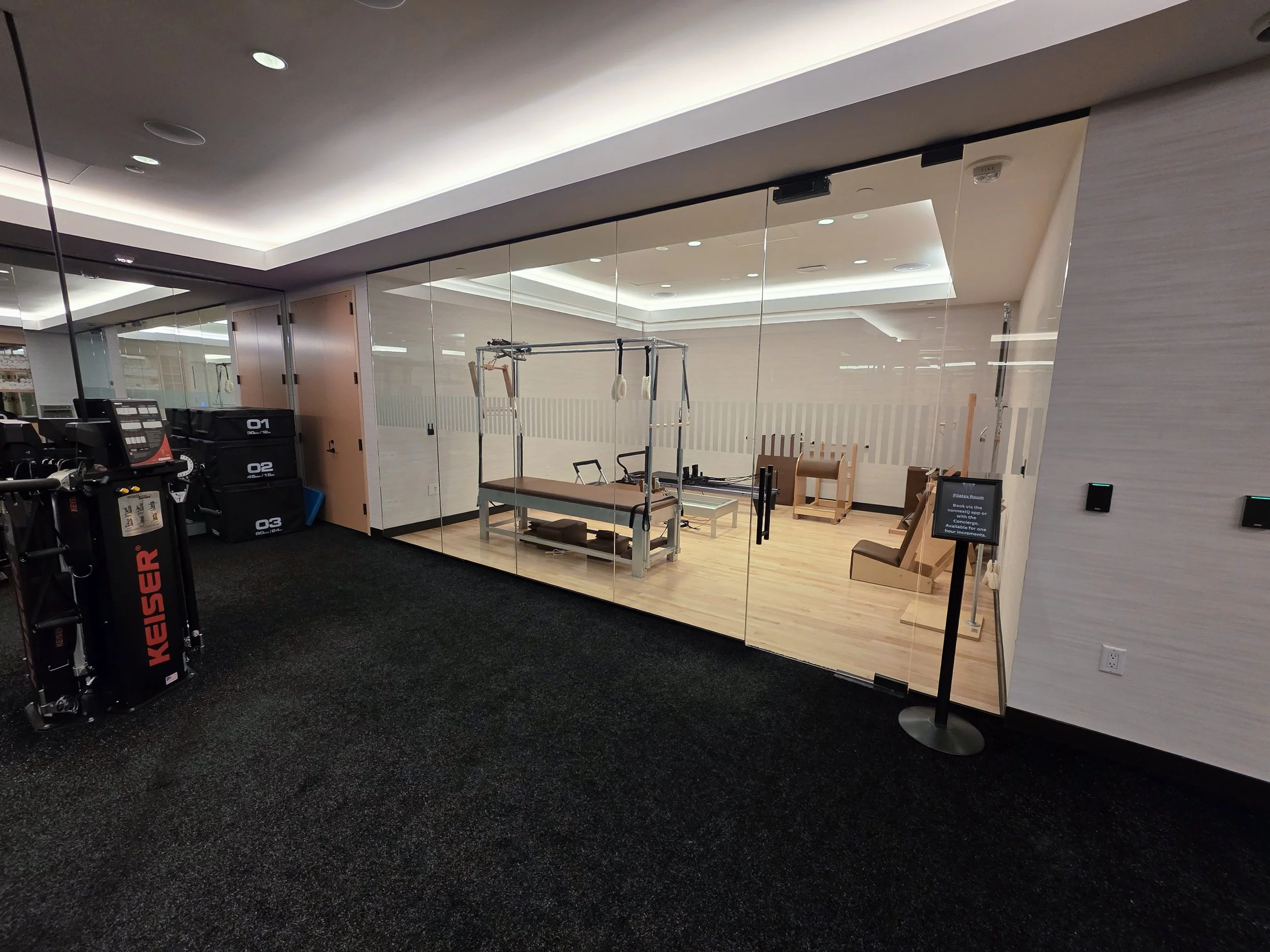 Fitness equipment and therapy chairs behind a glass wall in a wellness center