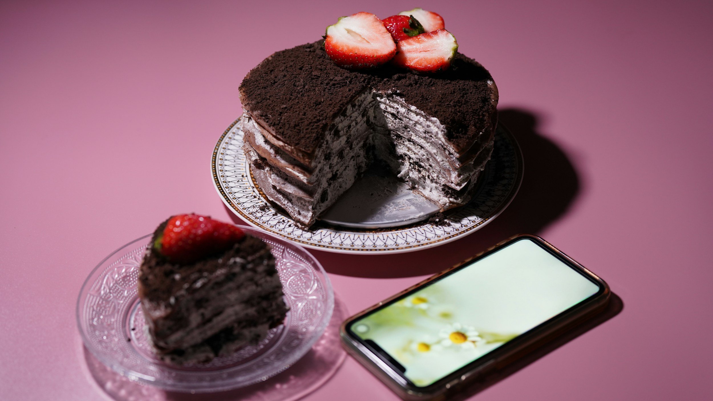 a chocolate and cherry cake sitting on a purple table with an iphone in the background