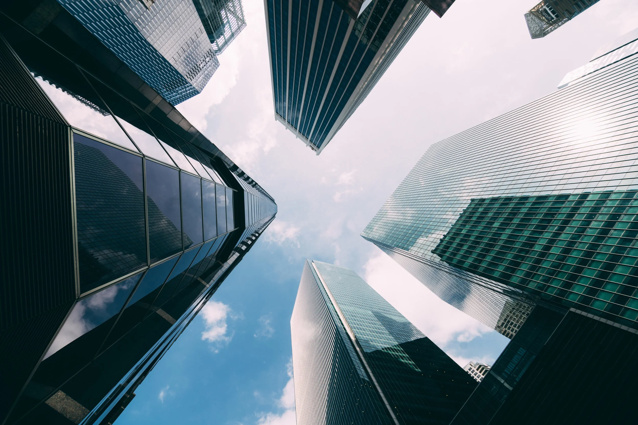 Looking up at tall glass skyscrapers in a city.